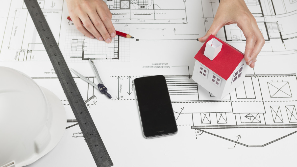 Une petite maison est posée sur un plan de construction.